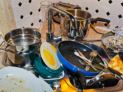 Ein Spülbecken mit schmutzigem Geschirr, Töpfen und Besteck.